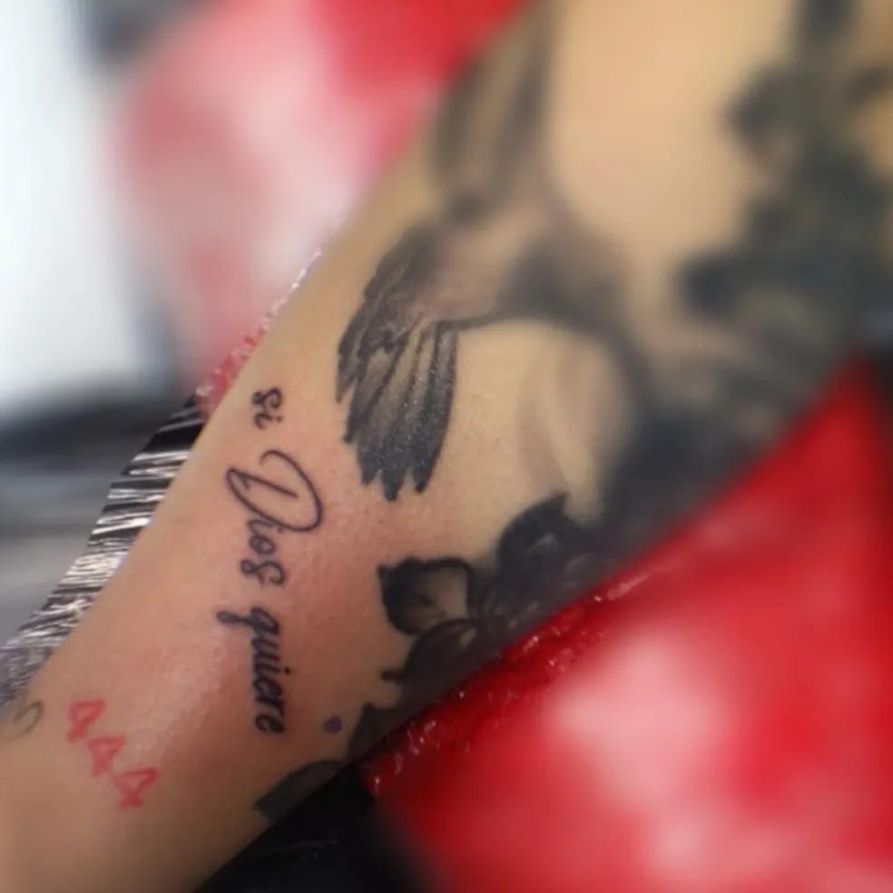 Tatuaje con ave y texto en el brazo